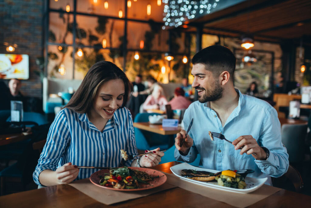 Two people smile and enjoy a meal at a warmly lit restaurant in St. George, LA.
