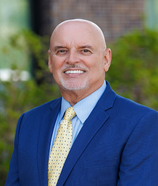 Bald, smiling man in a blue suit and yellow tie represents the City of St. George.